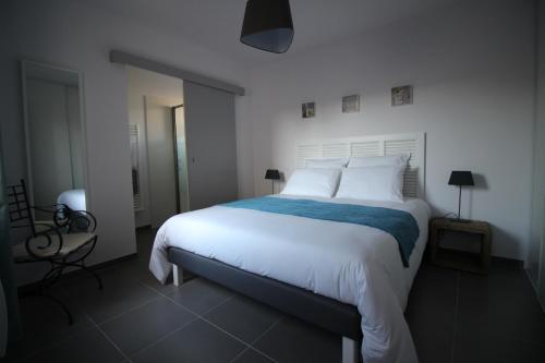 a bedroom with a large white bed and a chair at Le Clos de la Montagnette - Maison avec parking et jardin in LʼIsle-sur-la-Sorgue