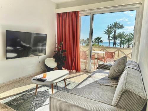 a living room with a couch and a large window at Yialos Village by Cybarco in Larnaca
