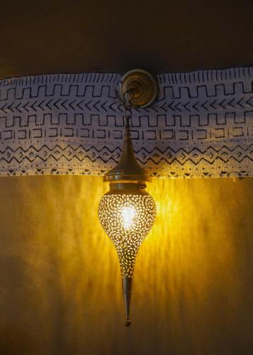 a lamp hanging from a wall with a light at Aladdin merzouga camp in Merzouga