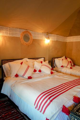 a bedroom with two beds with red and white pillows at Aladdin merzouga camp in Merzouga
