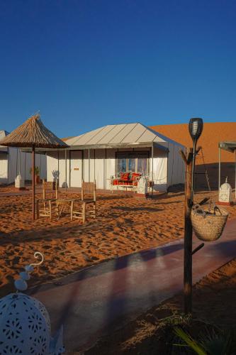 a building with a table and chairs in front of it at Aladdin merzouga camp in Merzouga