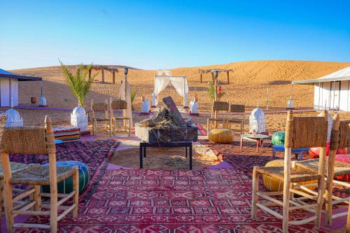 a woman sitting on a table in the desert at Aladdin merzouga camp in Merzouga