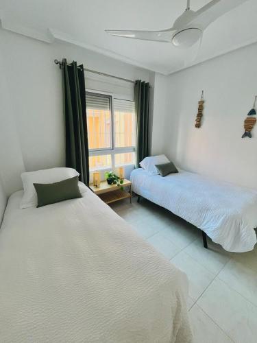 a bedroom with two beds and a window at Casa Rivero in Los Alcázares