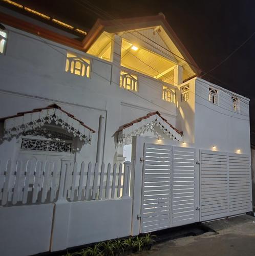 a white house with a white fence and a gate at Sudu Colonial House 1929 in Ambalangoda