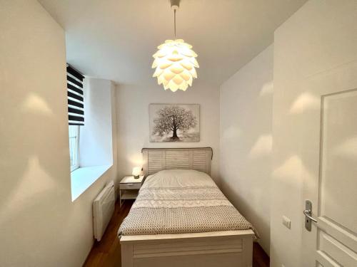 - une petite chambre avec un lit et un lustre dans l'établissement Au cœur de Colmar, à Colmar