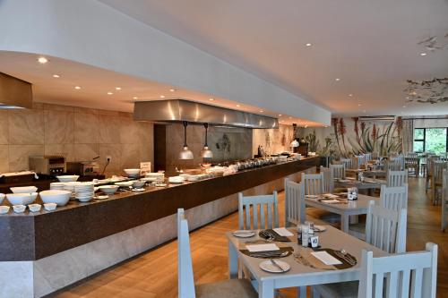 a restaurant with a long counter with white tables and chairs at Champagne Castle Hotel in Champagne Valley