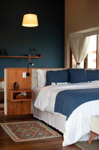 a bedroom with a bed with a blue wall at Lavandas de Cunha Pousada Boutique in Cunha