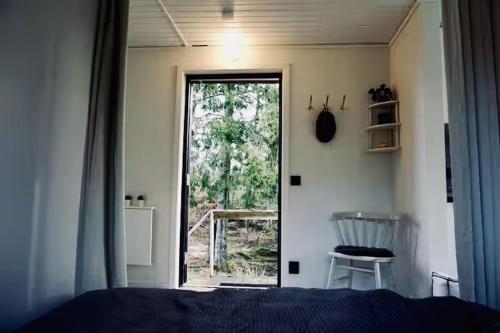 ein Schlafzimmer mit einem Bett und einer Glasschiebetür in der Unterkunft Tiny House with a Stunning Lake View 30 Min from Gothenburg in Gråbo
