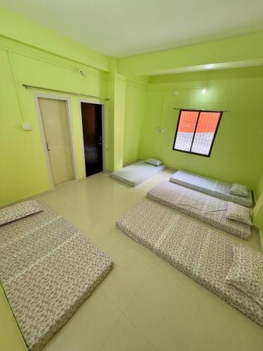 3 camas en una habitación con paredes verdes y ventana en Rishal Niwas Homestay, en Guwahati