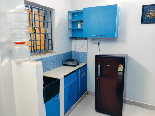 a small kitchen with blue cabinets and a refrigerator at Studio Apartment with private entrance, behind DLF and near L&T, RMZ IT park and close to SRMC & MIOT Hospital in Chennai