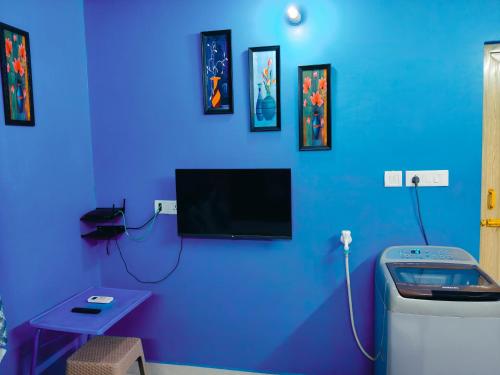 a blue room with a toilet and a tv on the wall at Studio Apartment with private entrance, behind DLF and near L&T, RMZ IT park and close to SRMC & MIOT Hospital in Chennai