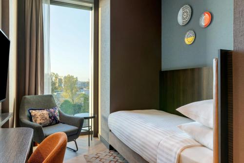 a bedroom with a bed and a chair and a window at Corendon Amsterdam New-West, a Tribute Portfolio Hotel in Amsterdam