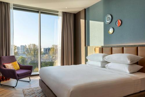 a bedroom with a bed and a chair and a large window at Corendon Amsterdam New-West, a Tribute Portfolio Hotel in Amsterdam