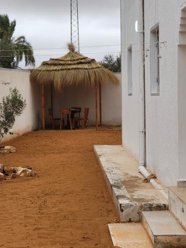 a house with a straw umbrella and a table and chairs at Sassi Villa in Arkou