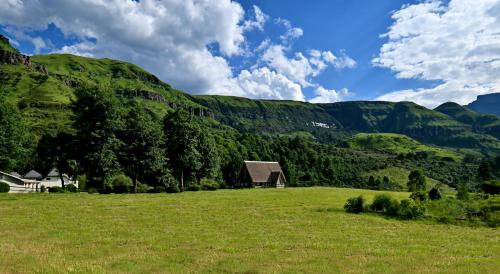an open field with a barn in the mountains at Champagne Castle Hotel in Champagne Valley