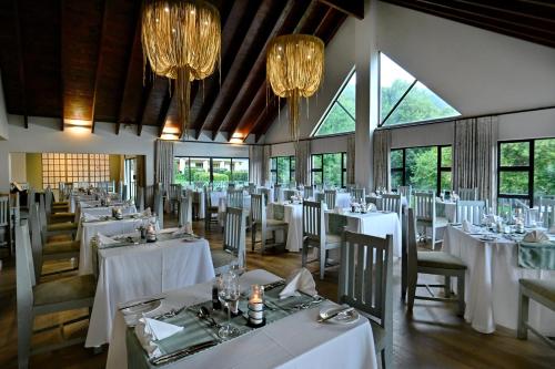 a dining room with white tables and chairs and chandeliers at Champagne Castle Hotel in Champagne Valley