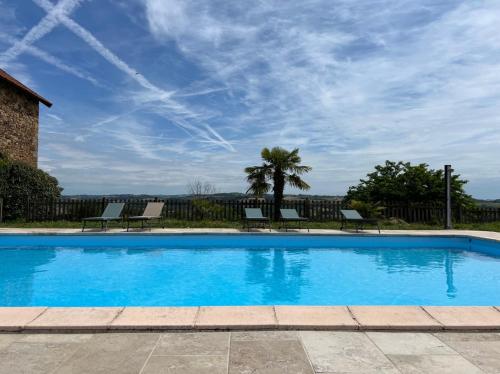 - une piscine avec des chaises et un ciel bleu dans l'établissement Gîtes & Chambres d'hôtes Peyrecout, à Laparrouquial