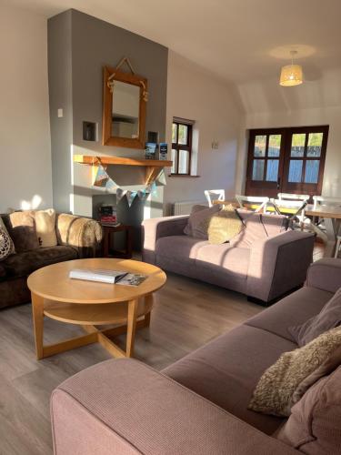 un salon avec deux canapés et une table dans l'établissement Tavnaghoney Cottages, à Cushendall