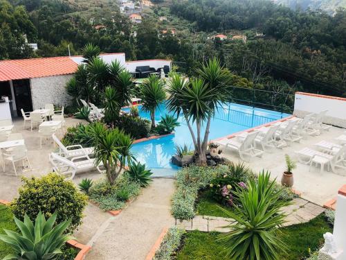 a resort with a swimming pool and chairs and trees at House in caniço in Ribeirinha