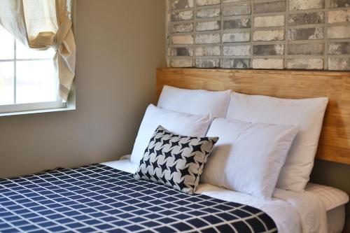 a bed with white pillows and a brick wall at Adellia Pension in Gyeongju