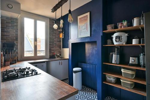 une cuisine avec des murs bleus et un comptoir. dans l'établissement La vie en couleurs, au Havre