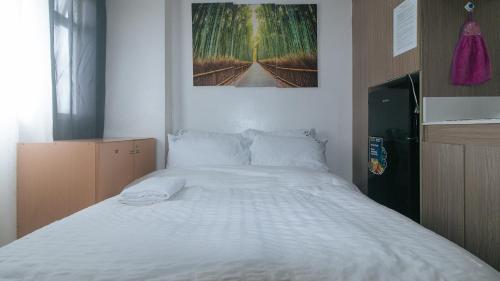 a bedroom with a white bed with a picture on the wall at Eimy's Place at Urban Deca Mandaluyong by RedDoorz in Manila