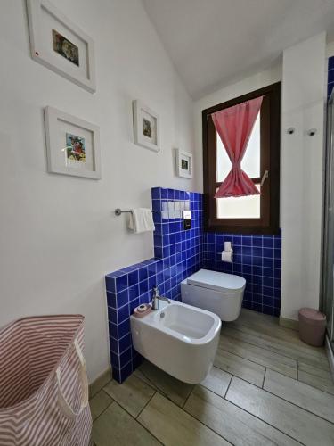 a blue tiled bathroom with a toilet and a sink at Sa Mirada Apartments in Villasimius