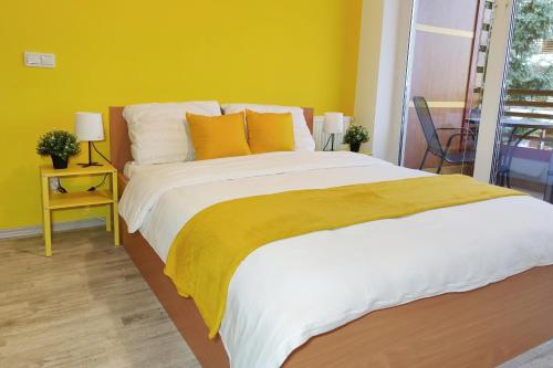 a bedroom with a large bed with a yellow wall at Apartment Marusa in Moravske Toplice