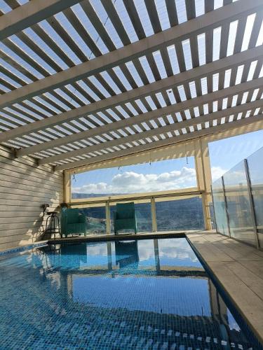 una gran piscina con techo de madera y ventanas en צימר old school, en Ein Kinya