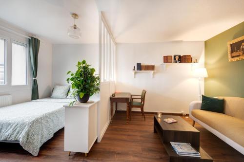 a bedroom with a bed and a couch and a table at Appartement proche du Parc de la Tête d'Or - Garage Gratuit in Villeurbanne