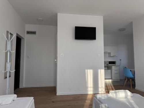 a white room with two beds and a television on a wall at VESTA Apartamenty P23 in Szczecin
