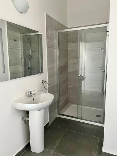 a white bathroom with a sink and a shower at Stylish Boutique Duplex Apartment Home - Green - 2 Large Double Bedrooms with Ensuite Bathrooms in Msida