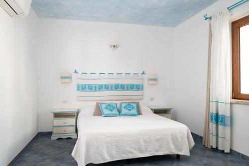 a bedroom with a white bed with two blue pillows at Residence Solaria in Budoni