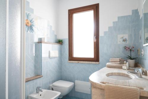 a blue bathroom with a sink and a toilet at Residence Solaria in Budoni