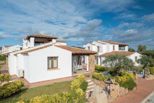 a large white house with a stone wall at Residence Solaria in Budoni