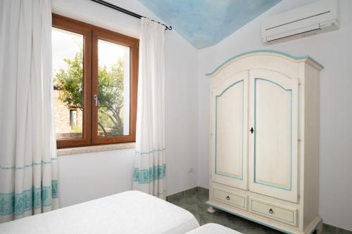 a bedroom with a white cabinet and a window at Residence Solaria in Budoni