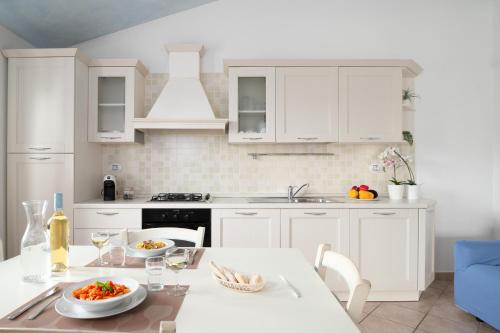 a kitchen with white cabinets and a table with food at Residence Solaria in Budoni