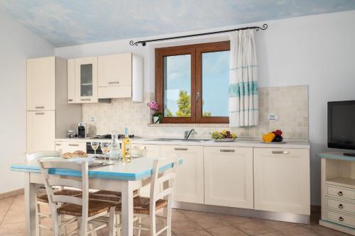 a kitchen with white cabinets and a table with chairs at Residence Solaria in Budoni