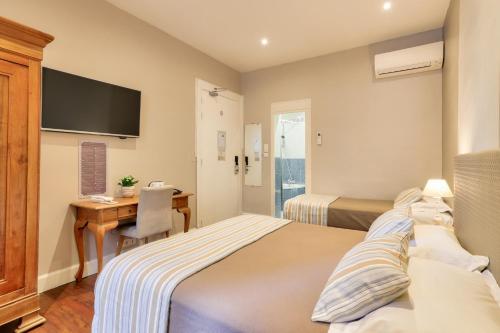 a bedroom with two beds and a desk with a computer at Hotel Lepante in Nice