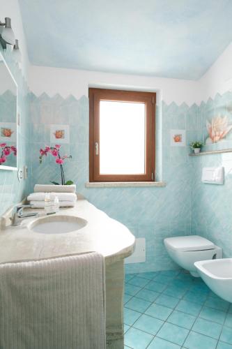 a bathroom with a sink and a toilet and a window at Residence Solaria in Budoni