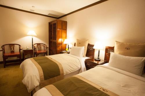 a hotel room with two beds and two lamps at Rich Garden Hotel in Taipei