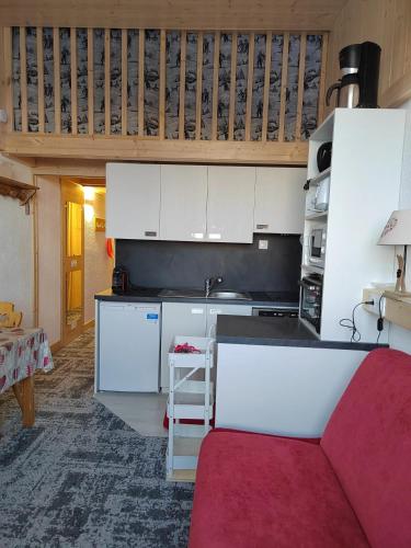une cuisine avec des placards blancs et un canapé rouge dans l'établissement Studio chaleureux à Aime la Plagne 25 m² en montagne, à Aime La Plagne
