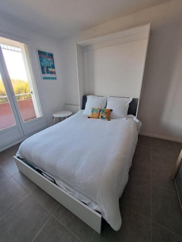 une chambre avec un grand lit blanc avec une fenêtre dans l'établissement studio proche Narbonne centre, à Narbonne