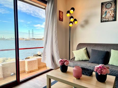 un salon avec un canapé et une vue sur l'eau dans l'établissement Voile de Mer - 2 Studios Bord de Mer, 2 SDB, CLIM, 5 personnes, à Fos-sur-Mer
