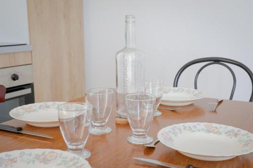 a table with plates and glasses and a bottle on it at Appartement rez de chaussée à Beaupréau en Mauges in Beaupréau