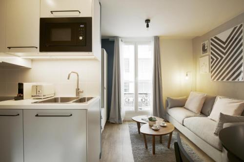une cuisine et un salon avec un canapé dans l'établissement Stay in a Designer Apartment with Private Terrace, à Paris