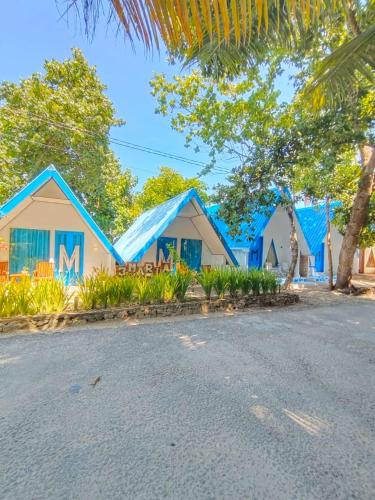 a row of houses with blue roofs on a street at Tria Maria Cottage in Ngurblut