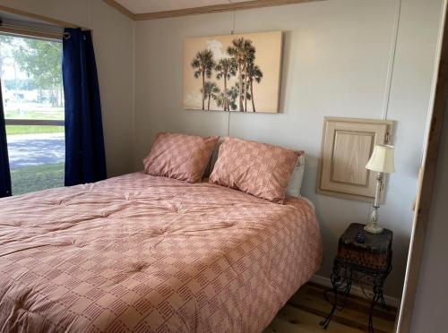 a bedroom with a bed with a pink comforter and a window at Amazing 1 bedroom Near Disney in Seven Points