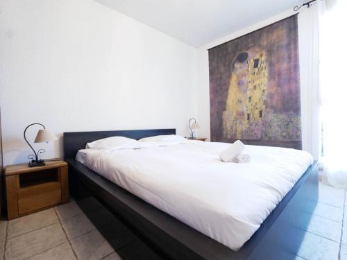 - une chambre avec un grand lit blanc et un tableau dans l'établissement Le Camarguais - TERRASSE ET PARKING, à Montpellier