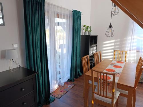 a dining room with a wooden table and green curtains at Bukszpanowa Alejka domek całoroczny, okolica Ojcowski Park Narodowy in Milonki